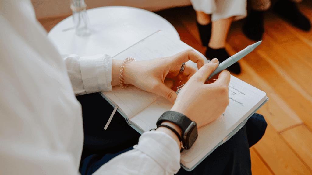 A dietitian holding a journal and pen, attentively taking notes during a nutrition counseling session with a client.