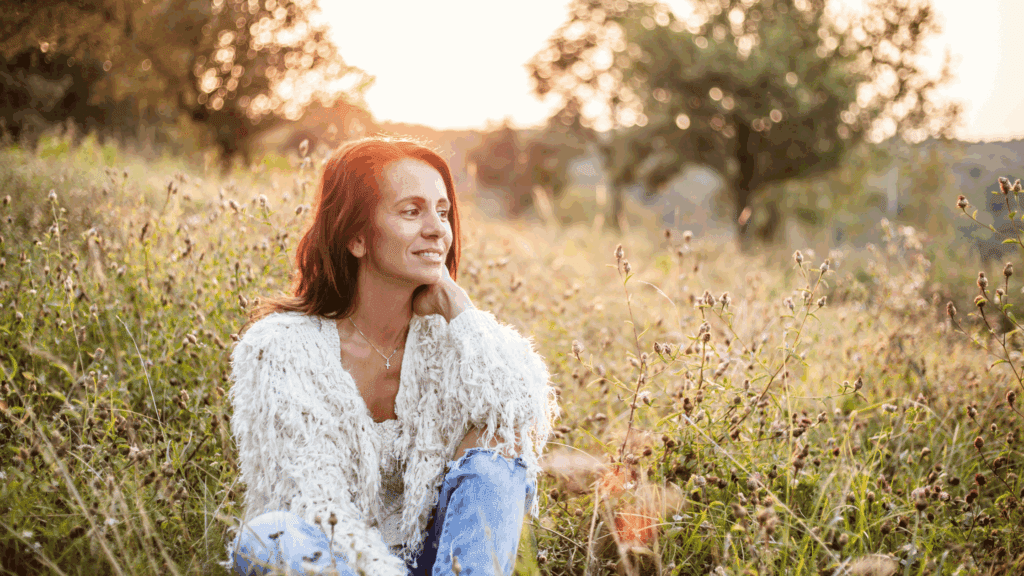 Happy woman sitting in field of flowers enjoying life after working with a nutritionist for menopause.