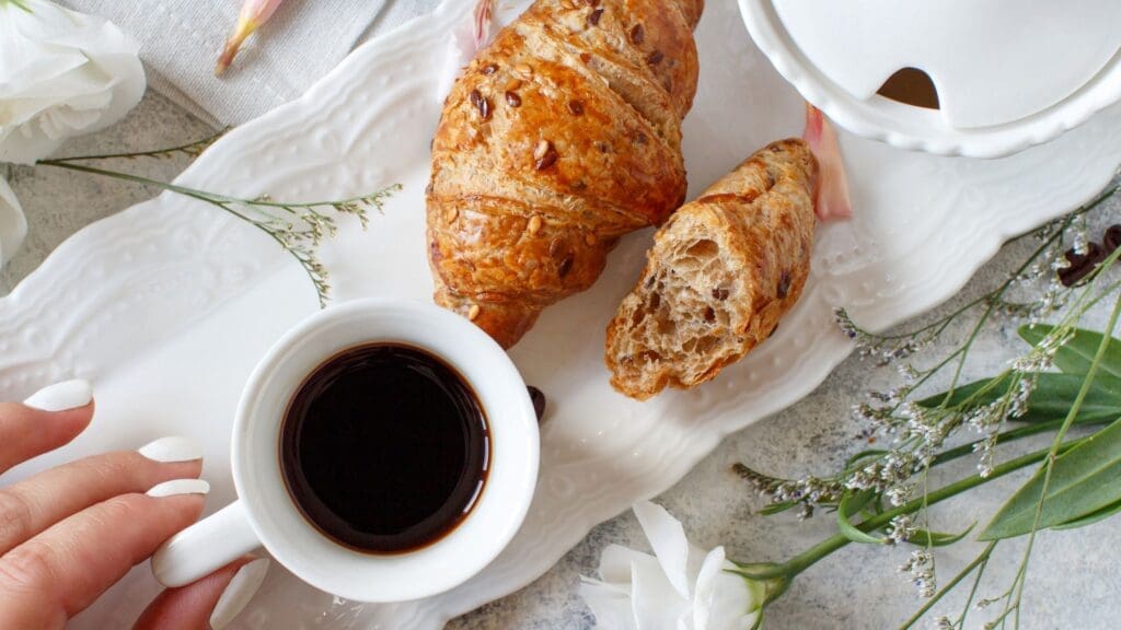 A overhead view of croissants and coffee on a white tray, representing the connection between ADHD and eating disorders.